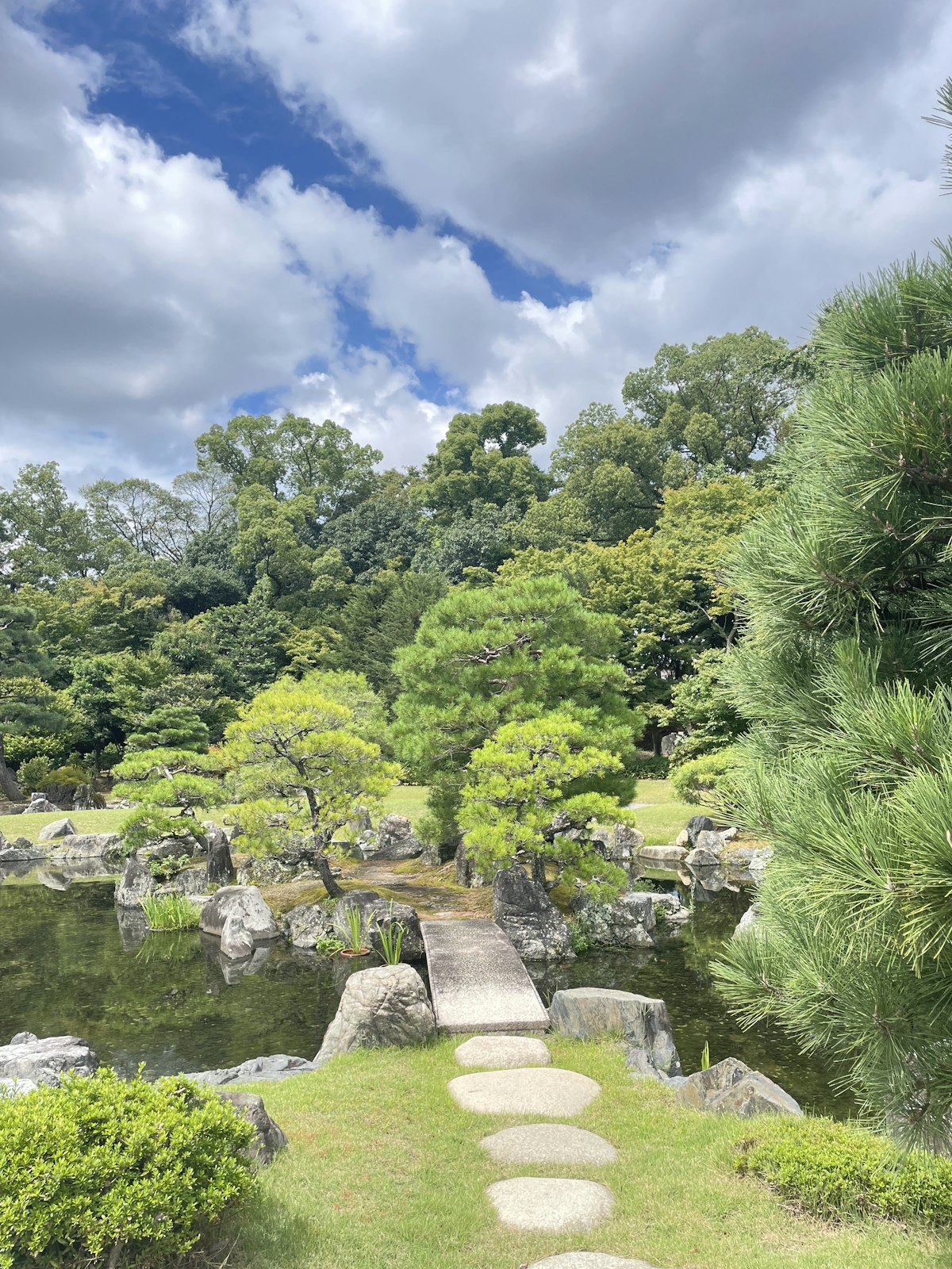 池と石畳の小道がある、手入れされた日本庭園
